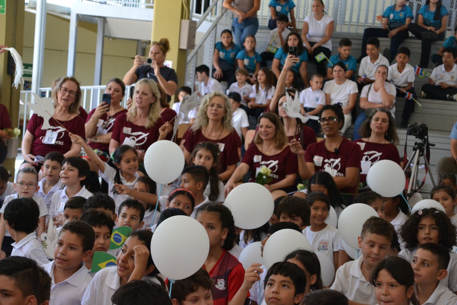 Audience with balloons and paper doves celebrating during a Choral Fest Costa Rica school event.
